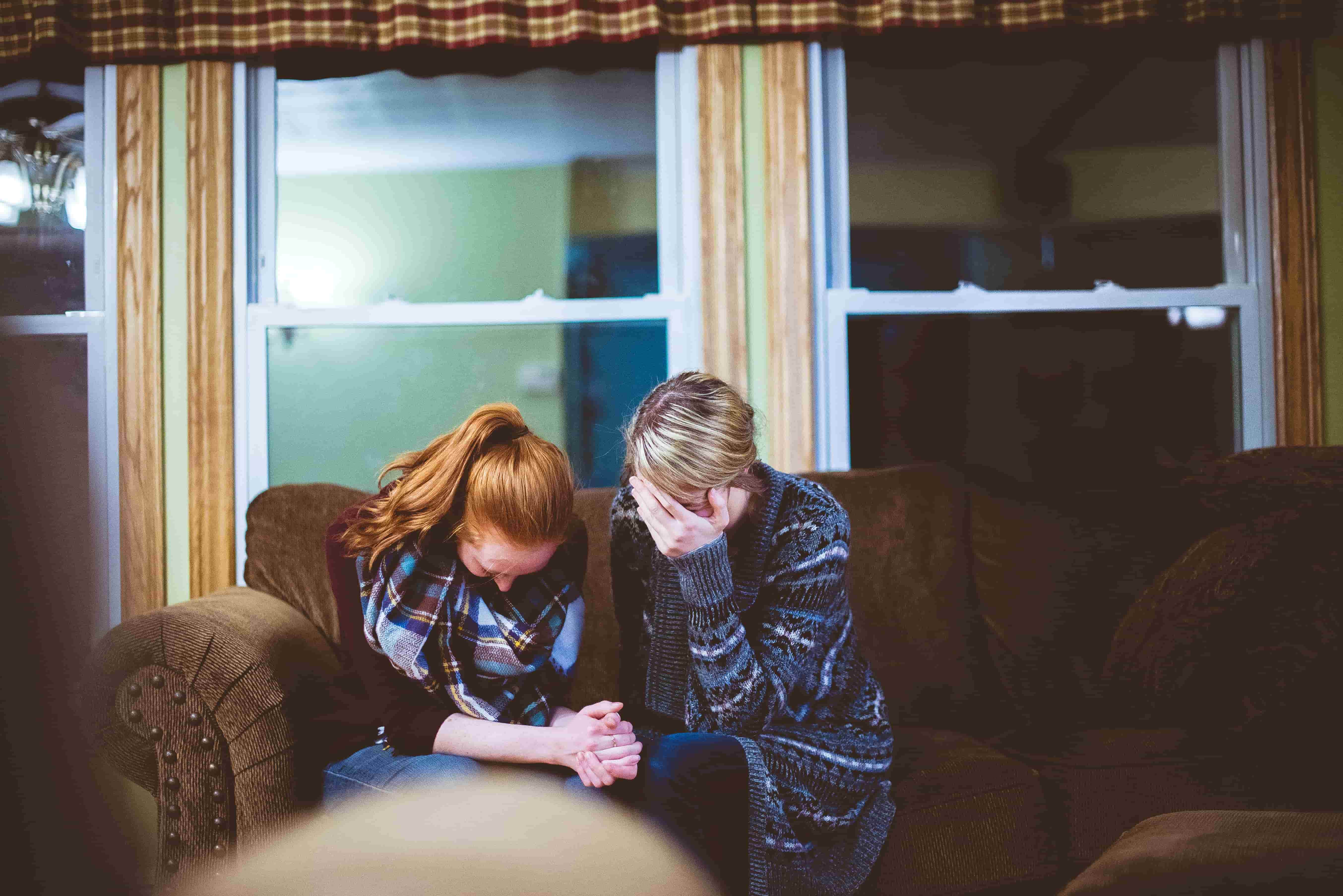 Two grieving women sat together crying